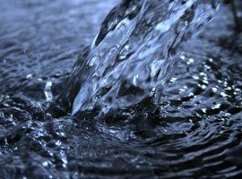 Close up of water being poured into a large volume of water